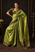 Woman wearing a green saree with a textured wall background