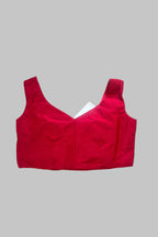 A bright red sleeveless crop top or bralette with a scoop neckline, laid flat on a wrinkled gray fabric background.