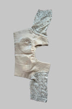 A vintage beige satin garment piece with intricate silver beadwork and lace trim, laid flat on a gray fabric background.