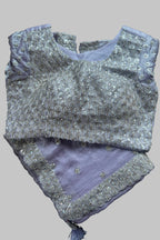 A lavender purple and silver embellished traditional Indian outfit laid flat on a dark gray fabric background. The top features intricate silver embroidery and beadwork over a lavender base, paired with a matching lavender bottom piece decorated with silver border embroidery.