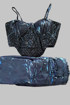 A two-piece outfit consisting of a black and blue beaded corset-style top and matching shiny blue pants, laid flat on a light gray fabric surface.