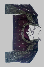 A dark plum purple embroidered blouse top with gold and silver mirror work and sequin borders, laid flat on a light blue fabric background.