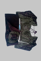A traditional Indian outfit laid flat on a white sheet, featuring a deep maroon velvet kurta with gold embroidery and a matching embroidered blouse.