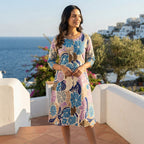 Woman wearing pastel floral cotton kurti standing on a luxury seaside terrace during golden hour.