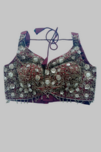 An ornate embellished blouse top with deep V-neckline, tie-back straps, and extensive silver mirror work and bead embroidery over a deep purple base, shown on a plain white background.