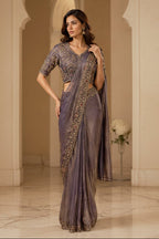 Two models wearing traditional Indian sarees side by side. The left model wears an olive green saree with gold embroidery, and the right model wears a dusty purple saree with gold embroidery.