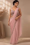 Three views of a woman modeling a sleeveless sari dress in soft dusty pink and light blue shades, shown in an elegant indoor setting with warm lighting and architectural details.