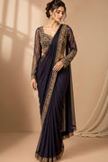 Three views of a woman modeling a traditional Indian saree in a studio setting. The saree has a deep navy blue body with a gold embroidered border, paired with a matching navy blue lace blouse, and is shown in three colorways: navy blue, dark navy blue, and deep purple.
