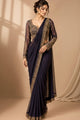 Three views of a woman modeling a traditional Indian saree in a studio setting. The saree has a deep navy blue body with a gold embroidered border, paired with a matching navy blue lace blouse, and is shown in three colorways: navy blue, dark navy blue, and deep purple.