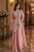 Woman in a pink saree with a matching blouse in an elegant indoor setting.