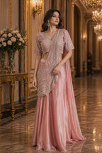 Woman in a pink saree with a matching blouse in an elegant indoor setting.