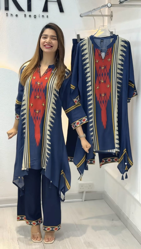 Woman wearing a blue and red traditional outfit with matching dupatta in a store setting.
