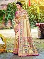 Woman wearing a traditional beige saree with colorful patterns in an outdoor setting.