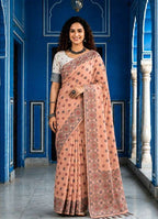 A woman models a peach-pink saree with brown and gold floral patterns, paired with a white sleeveless blouse. The image is a split-screen presentation showing a full-length view on the left and a close-up portrait on the right, set against a blue architectural background.