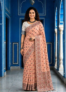 A woman models a peach-pink saree with brown and gold floral patterns, paired with a white sleeveless blouse. The image is a split-screen presentation showing a full-length view on the left and a close-up portrait on the right, set against a blue architectural background.