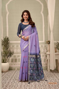 Woman wearing a purple saree with a patterned border indoors, with 'Gobuni' branding.
