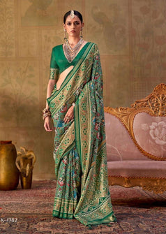 A split-panel catalog image showing a woman modeling a green and gold patterned saree in two elegant indoor poses. The left panel shows her standing, and the right panel shows her seated on a carved gold chair.