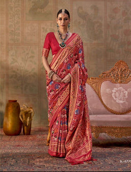 Woman in a traditional red saree with gold patterns, sitting on an ornate chair, with 'Kreshya' branding.