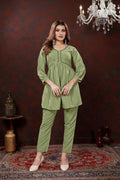 Woman modeling a green outfit in a room with a chandelier.