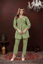 Woman modeling a green outfit in a room with a chandelier.