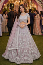 Woman in a traditional embroidered outfit at a festive event with decorations and people in the background.