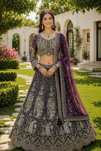 Woman in traditional embroidered outfit standing outdoors with a building and garden in the background