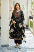 Woman in a traditional outfit with intricate patterns standing in an outdoor setting.