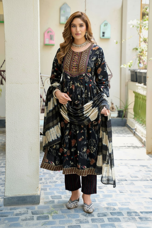 Woman in a traditional outfit with intricate patterns standing in an outdoor setting.