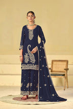 Woman wearing a navy blue embroidered traditional outfit with a beige background