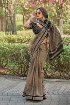 A woman modeling a brown and black patterned saree with a black embroidered blouse, standing outdoors in a park setting. The Siddharth Wearable brand logo is visible in the top right corner.