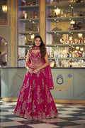 Woman in a pink embroidered dress standing in a bar with shelves in the background