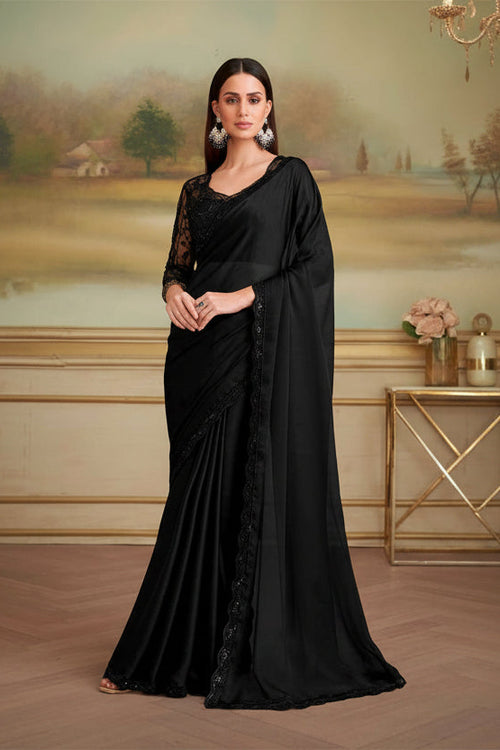 Woman in a black saree with lace detailing in an elegant indoor setting.