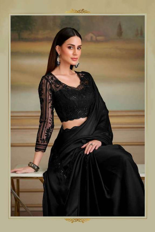Woman in a black saree with lace detailing in an elegant indoor setting.