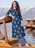 Woman in a blue floral dress on a boat with mountains in the background