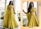 A woman modeling a bright yellow embroidered traditional outfit with a matching dupatta, shown in a split layout: a full-body view on the left and a closer cropped view on the right. The outfit has dense floral embroidery and mirror work, and the background is a light architectural interior.