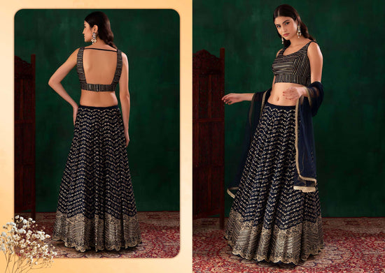 A woman modeling a black and gold embellished lehenga choli set, shown in two views: a back view on the left and a front view on the right, set against a dark green studio backdrop with a patterned rug.