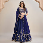 A woman modeling a purple lehenga choli set with ornate gold embroidery, shown in a split layout with a smaller inset view on the left and a full-body view on the right against an outdoor architectural background.